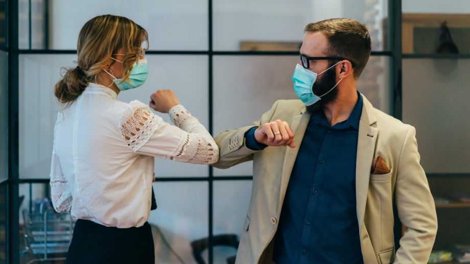 Colleagues in the office practicing alternative greeting for safety and protection during COVID-19